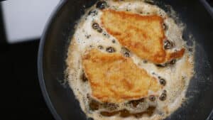 Two breaded fish fillets on Ztove non-stick pan with butter