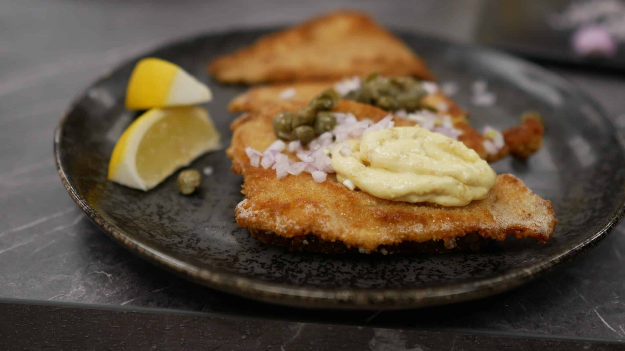 Ready-fried fish fillet with remoulade, capers, lemon and onions