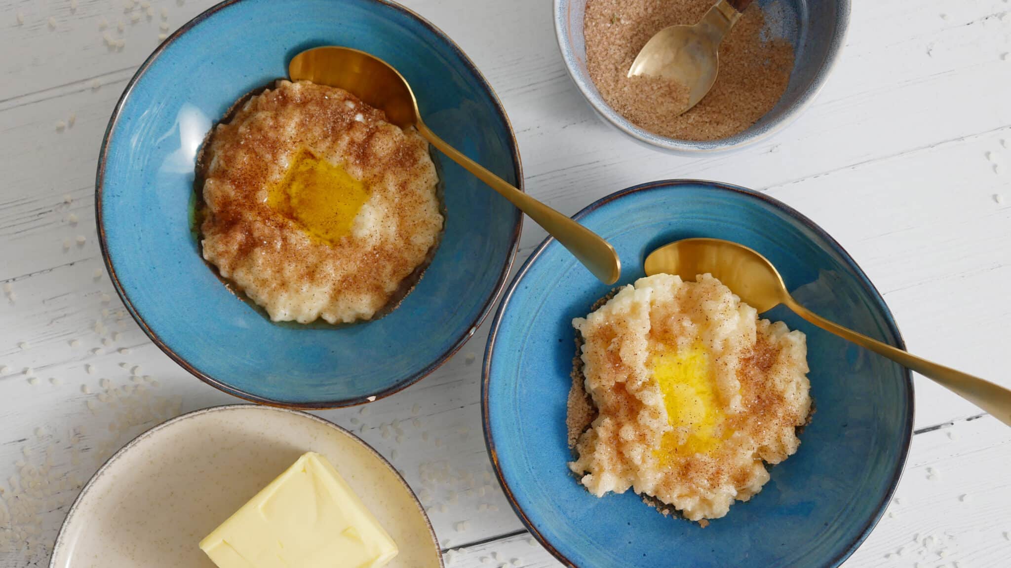 Two bowls of rice pudding, topped with cinnamon sugar and a dollop of butter.