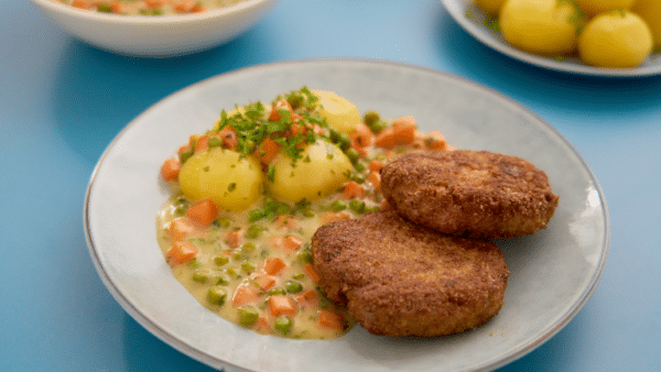Breaded pork patties with stewed peas and carrots